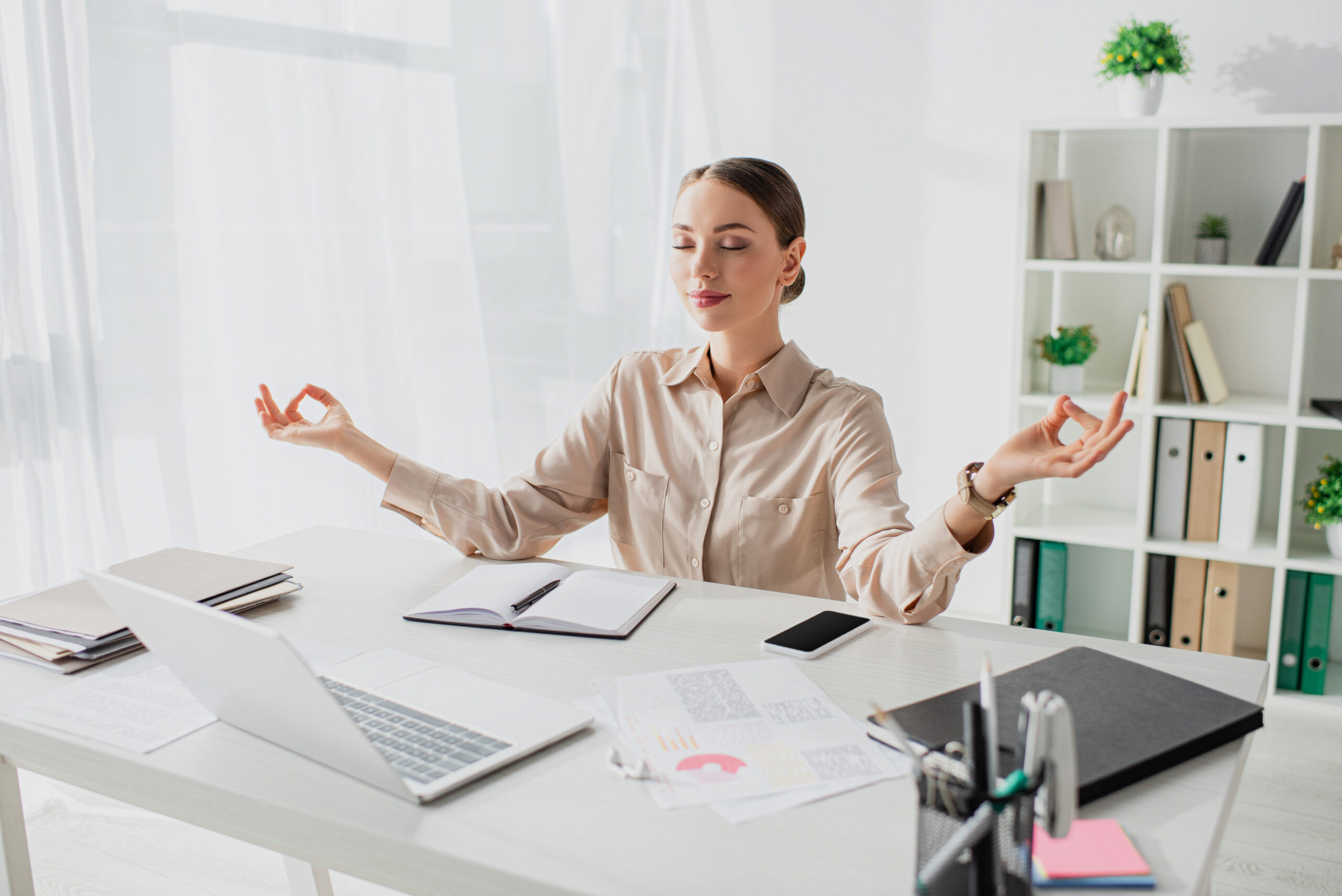 A woman practicing meditation to alleviate work-related stress in her office environment