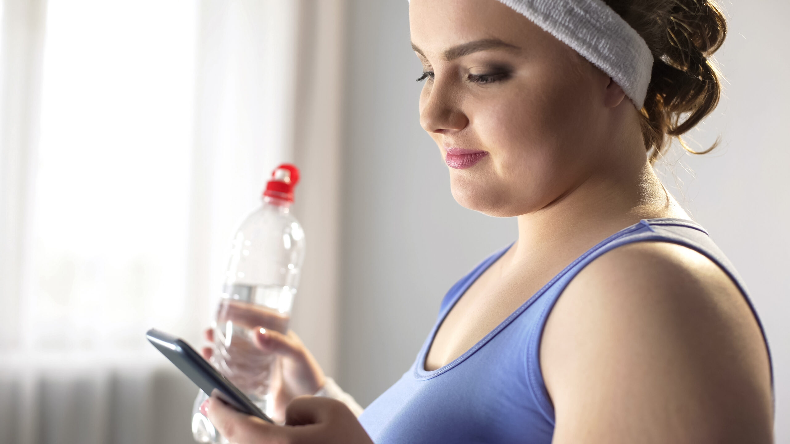 Plump lady scrolling on smartphone, looking for new tips to lose extra weight