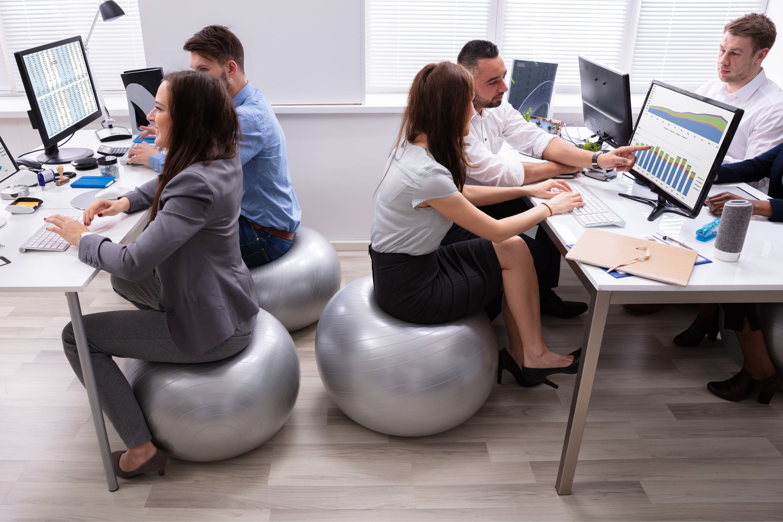 group of employee sharing ideas in workplace sitting on fitness ball